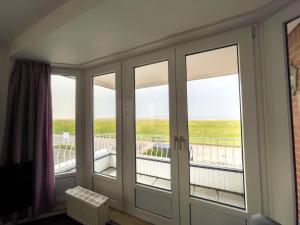 een kamer met glazen schuifdeuren en een balkon bij Haus-Nordseeperle-Fewo-Nr-6 in Cuxhaven