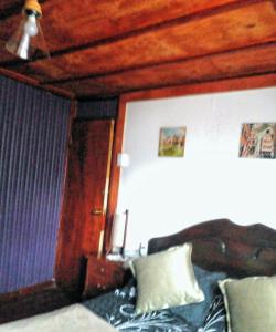 1 dormitorio con cama y techo de madera en Hostal Casa Galerna de La Montaña en San José de Maipo