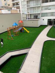 リマにあるLovely two bedroom apartment in Mirafloresの芝生の上に犬がいる遊び場付きのアパートメント +4枚の写真