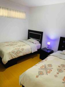 リマにあるLovely two bedroom apartment in Mirafloresのベッドが2つとテーブルの上にランプが置かれた寝室