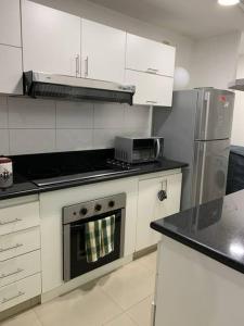 リマにあるLovely two bedroom apartment in Mirafloresの白いキャビネットとコンロ付きオーブンを備えたキッチン