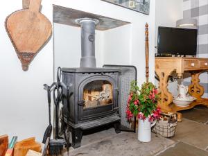 a wood stove in a room with a tv at Ivy Cottage in Ripon