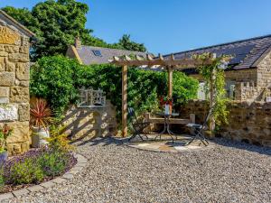 a patio with a table and a wooden pergola at Ivy Cottage in Ripon