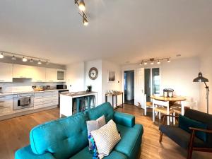 Bellevue Apartment في لارغس: غرفة معيشة مع أريكة زرقاء ومطبخ