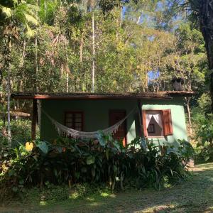 une petite maison verte avec un hamac en face de celle-ci dans l'établissement Pousada Sítio Itaúna, à Penedo