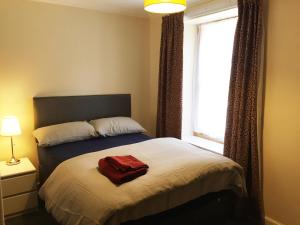 Un dormitorio con una cama con una toalla roja. en Dunbar Serviced Apartment, en Dunbar