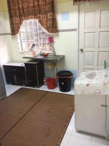 a kitchen with a table and a door and a counter at Guesthouse Adam in Pengkalan Cepa