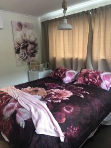 a bedroom with a bed with a flower blanket on it at Almost Heaven BNB in New Plymouth