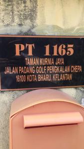een bord op een muur naast een roze koffer bij Guesthouse Adam in Pengkalan Cepa