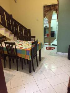 een eettafel met stoelen en een kleurrijke tafelkleed bij Guesthouse Adam in Pengkalan Cepa