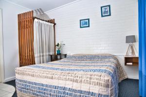 um quarto com uma cama com um cobertor azul e branco em Motel Myall em Dalby