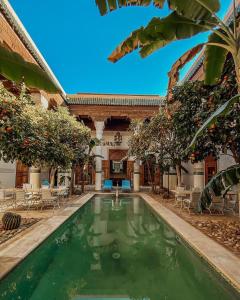 een zwembad op de binnenplaats van een huis met stoelen en bomen bij Riad Slitine & Spa in Marrakesh