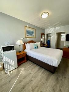 a hotel room with a large bed and a desk at The Palomar Inn in Pismo Beach