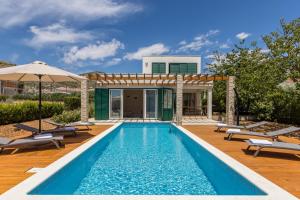 a pool with chairs and an umbrella next to a house at Villa Trogir save 15 percent on Split-villas com in Trogir