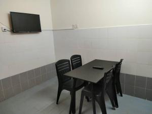 mesa con 4 sillas y TV en la pared en Homestay Kuala Terengganu near Batu Burok, Hospital HSNZ, KTCC Mall, Drawbridge C, en Kuala Terengganu