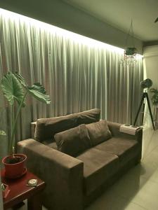 a living room with a couch in front of a curtain at Apt 1D Aeroporto/Arena in Porto Alegre