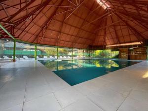 a large swimming pool in a building with a roof at Ecoamazonia Lodge in Puerto Maldonado