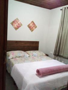 ein Schlafzimmer mit einem Bett und einem rosa Handtuch darauf in der Unterkunft Magia e lazer - Locação chalés - 12km do centro de Morretes in Morretes