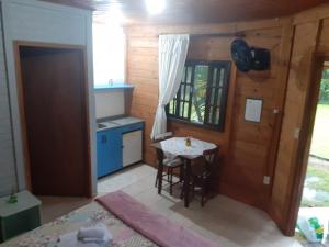 eine Küche mit einem Tisch und eine kleine Küche mit einem Fenster in der Unterkunft Magia e lazer - Locação chalés - 12km do centro de Morretes in Morretes