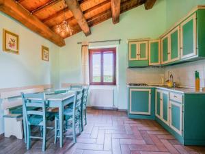 een keuken met groene kasten en een tafel en stoelen bij Quiet holiday home in Sellano with swimming pool a few kilometers from Rasiglia in Sellano