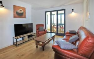 uma sala de estar com um sofá de couro e uma televisão em Cozy Apartment In Reauville With Wifi em Réauville