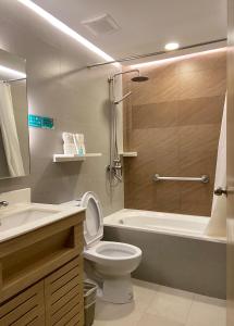 a bathroom with a toilet and a tub and a sink at Microtel by Wyndham Tarlac in Tarlac
