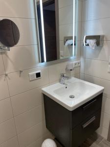 ein Bad mit einem Waschbecken und einem Spiegel in der Unterkunft Gästehaus Janßen in Cuxhaven