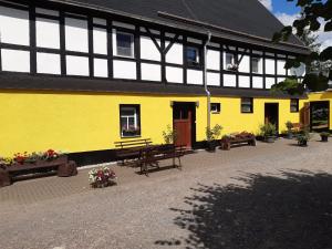 a yellow building with benches and flowers in front of it at Ferienwohnung auf dem Land in Dittersbach