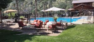 una piscina con sillas, mesas y sombrillas junto a en Rustic Rooms by Kings Canyon & Sequoia National Parks, en Squaw Valley