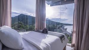 a bed in a room with a large window at Waenis Sunset View Hotel and Restaurant, Amed, Bali in Amed