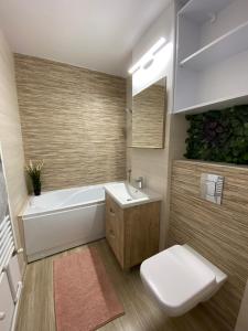 a bathroom with a tub and a toilet and a sink at Grove Apartment in Buzău