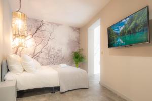 a bedroom with a white bed and a tv on a wall at Art Apartment newly build 7min from Rotterdam CS app1 in Schiedam