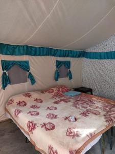 a bed in a tent with a bedsheet with flowers on it at Mussoorie Camp Resort in Mussoorie