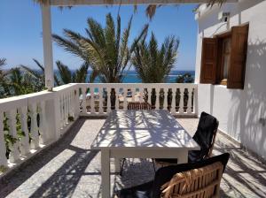 - une table et des chaises blanches sur un balcon donnant sur l'océan dans l'établissement Palmhouses, à Afiartis