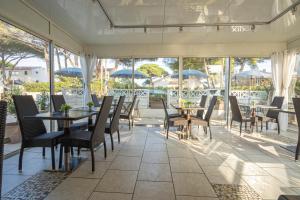 a dining room with tables and chairs and windows at Hôtel Le Méditerranée in Hyères