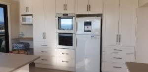 a white refrigerator in a kitchen with white cabinets at A Sweet Escape in Bridport
