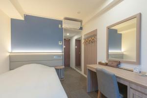 1 dormitorio con cama, escritorio y espejo en Libre Garden Hotel, en Naha