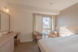 a hotel room with a bed and a desk and a window at Libre Garden Hotel in Naha