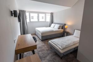 a small room with two beds and a table at ROOMERS in Maribor