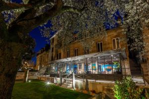 een gebouw met een boom ervoor bij Hôtel De Charme Le Chêne Vert in Brive-la-Gaillarde