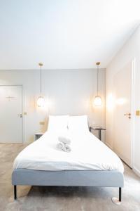 een slaapkamer met een groot wit bed en 2 verlichting bij The Den Newly Build Apartment 7-Minutes From Rotterdam City Central Station app2 in Schiedam