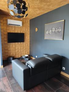 ein Wohnzimmer mit einem schwarzen Ledersofa und einem TV in der Unterkunft Océan d'amour & spa in Saint-Vivien
