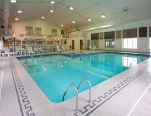 a large swimming pool with blue water in a building at Dunes Express Inn and Suites in Hart