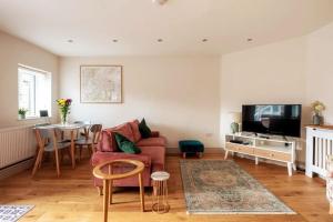 a living room with a red couch and a table at Y Cwtsh in Llandeilo