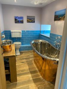 a bathroom with a tub and a toilet and blue tiles at Contemporary living with amazing views. Pembrokeshire in Pembrokeshire