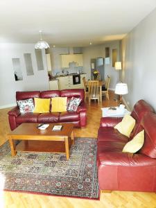 ロンドンデリーにあるDerry-Londonderry city centre waterfront appartmentのリビングルーム(赤い革張りのソファ、テーブル付)