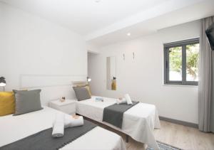 a white room with two beds and a window at In Downtown - Villa Serenity in Albufeira