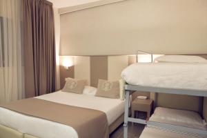 2 stapelbedden in een hotelkamer met een klein bed bij L'Hotel in Rimini
