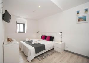 a white bedroom with a large bed with pink pillows at In Downtown - Villa Serenity in Albufeira