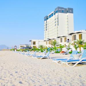 a row of chaise lounge chairs on the beach at Mirage Bab Al Bahr Beach Hotel in Dibba